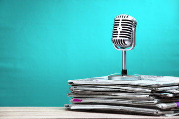 Retro microphone with newspaper on wooden table - announcement concept