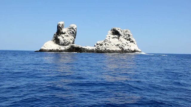 Birds on rock in middle of ocean in Pacific ocean. Unique amazing video footage. Abyssal relax water landscape. Mountain in sea.
