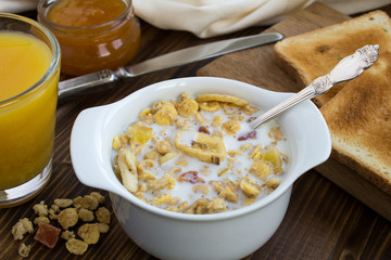 Muesli with milk in the white plate on the wooden background
