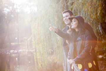 Smiling happy gourgeous couple walking in autumn park near a lake