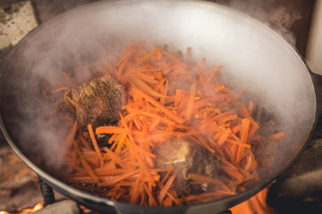 Cooking plov in the cauldron. Only meat, onions and carrots in the cauldron. Field kitchen.