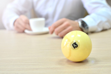 Billiard ball with number thirteen on a table with a businessman on a background. Concept of risk and luck in business.