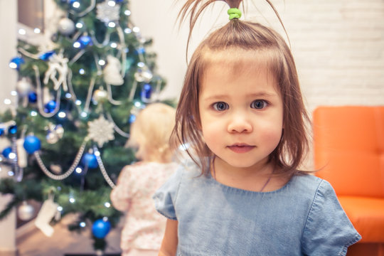 Beautiful baby girl with Christmas tree on background  in home