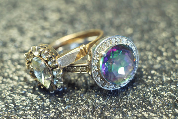 Two rings with precious stones on a brilliant background.