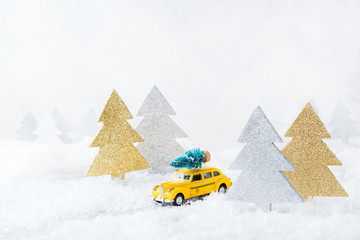 Toy car carrying christmas tree in a snow forest