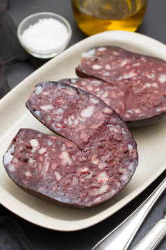 smoked sausage morcela on white dish on wooden background