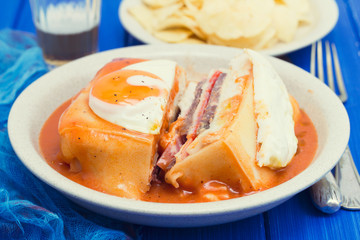 traditional portuguese sandwich with sauce francesinha on dish