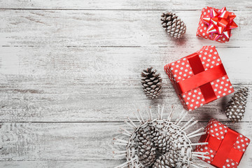 Composition of xmas, gift background packed in red packaging with colorful decorative pine cones, white background with modern gifts, happiness for loved ones