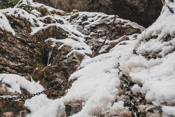 Fototapeta na wymiar Snowy cliffs with chains for hiking
