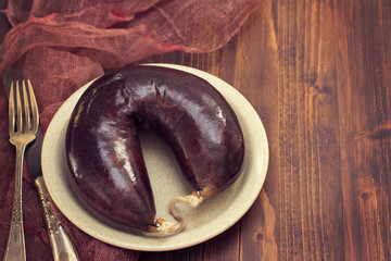 smoked blood sausage on white dish on wooden background