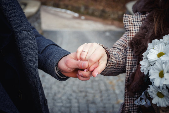 man holds the hand of a girl with golden rings