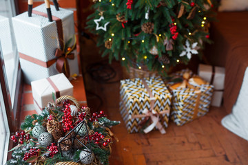 Closeup of a large stack of wrapped Christmas presents of varying sizes and shapes in Xmas interior.