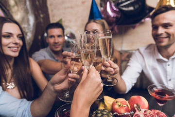 Young people are resting in a trendy nightclub. They clink glasses and drink champagne.