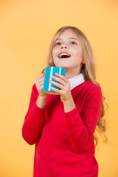 Child with surprised face hold blue cup on orange background