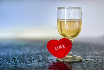 Lovely valentines comemoration clear glass goblet and Love heart on glass table with waterdrops