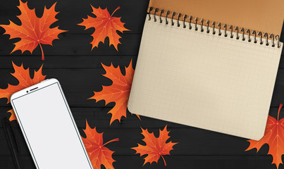 notebook, phone are lying on a wooden table with yellow, autumn leaves - 181540622