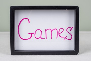 Text word games, in black frame, on white table.