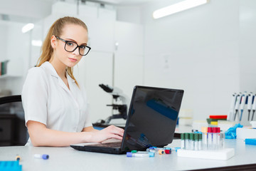 Modern technology in science. Scientist entering data of research results to laptop at laboratory