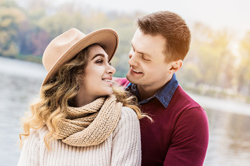 She means everything him. Portrait of young handsome man embracing his beautiful girlfriend while standing outdoors. Man and woman looking at each other and smiling. Togetherness and love concept.