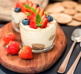 Homemade italian dessert tiramisu with strawberries, mint and blueberry in glass