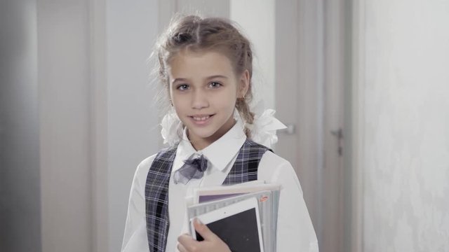 Cute pretty girl with books on white background with books and tablet smiling and happy at home, female little student
