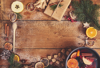 Mulled wine in saucepan  with spices and ingredients on wooden background. Top view, flat lay. Copy space for your text.