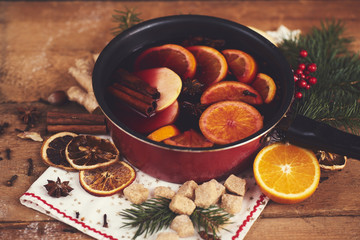 Mulled wine in saucepan  with spices and ingredients on wooden background. Top view, flat lay. Copy space for your text.