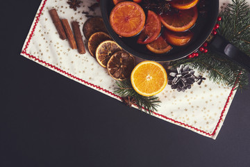 Mulled wine in saucepan  with spices and ingredients on black background. Top view, flat lay. Copy space for your text.