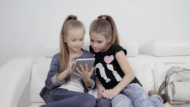 Girls with a tablet. Portrait of two female friends indoors. Two Teenage Girls Looking At Laptop tablet pc.