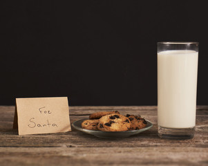 chocolate cookies for Santa and glass of milk on wood board