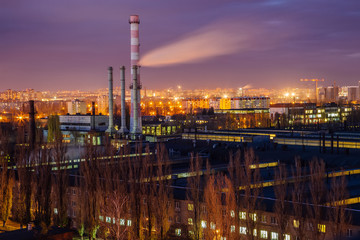 Night cityscape view of Voronezh. Industrial area, pipes of factory are polluting air