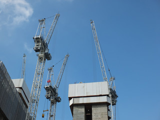 Fototapeta na wymiar construction cranes working in a large development site with concrete large structure with blue sky