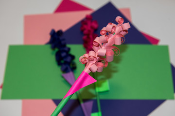 Children's handicraft paper flowers made of colorful paper and glue. Rolled up paper