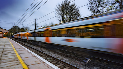 Obraz premium Pociąg podmiejski odjeżdża ze stacji o zmierzchu