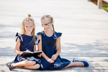 Adorable little school girls with notes and pencils outdoor. Back to school.