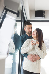 multiethnic couple enjoying morning coffee by the window