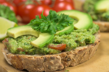 Healthy homemade guacamole. Traditionally mexican dish. Lime, tomato, parsley on the background
