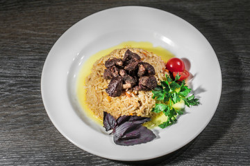A tasty dish of rice on a plate. On a wooden background