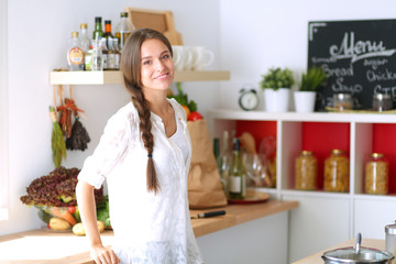 Young woman standing near desk in the kitchen. Young woman .
