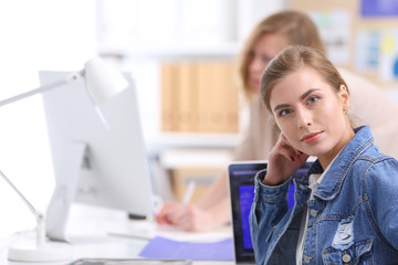 Two young woman sitting near desk with instruments, plan and laptop.