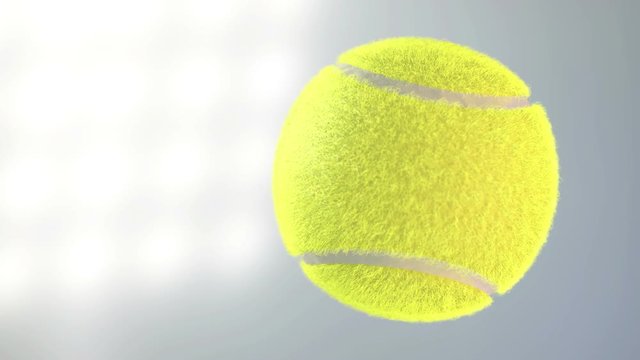 A tennis ball spinning in slow motion flying through the air on a floodlit stadium background at night