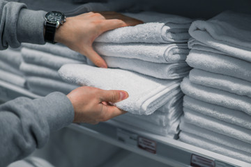 Male Customer inspecting and buying towels in supermarket. White clean towels