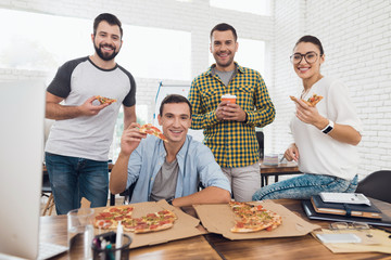 Office workers and man in a wheelchair are eating pizza. They work in a bright and modern office.