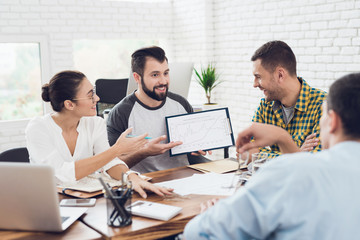 A man demonstrates business graphics. His collegues are listening to him.