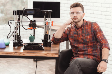 Fototapeta na wymiar A man is posing near the 3d printer on which he just printed an apple model. He is very pleased with the result.