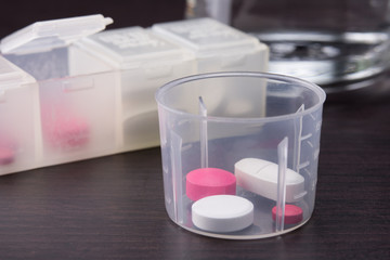 pills in the medicine cup and a white pill box on the table. selective focus