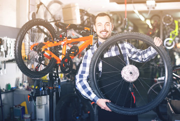 man in apron considering composition of wheel for bicycle