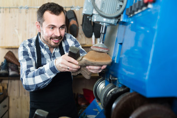 male worker fixing failed shoes in shoe repair workshop