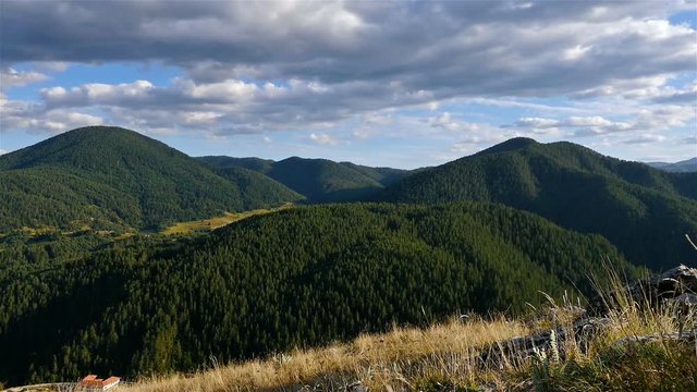 Time lapse of Fluffy clouds over low mountains covered with dense forests