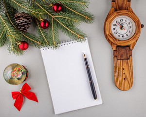 Empty sheet of paper, pen, a spruce branch and Christmas-tree toys on a light gray background. With copy space. Business desk table concept.